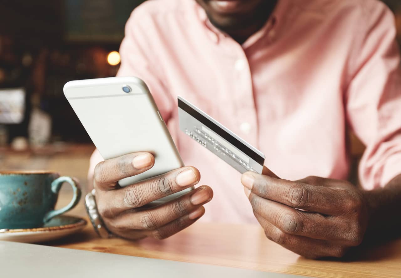 A person holds a mobile phone and a credit card