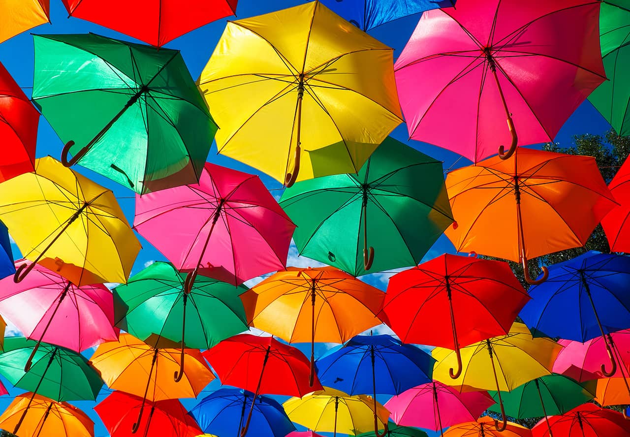 many colorful open umbrellas as seen from below