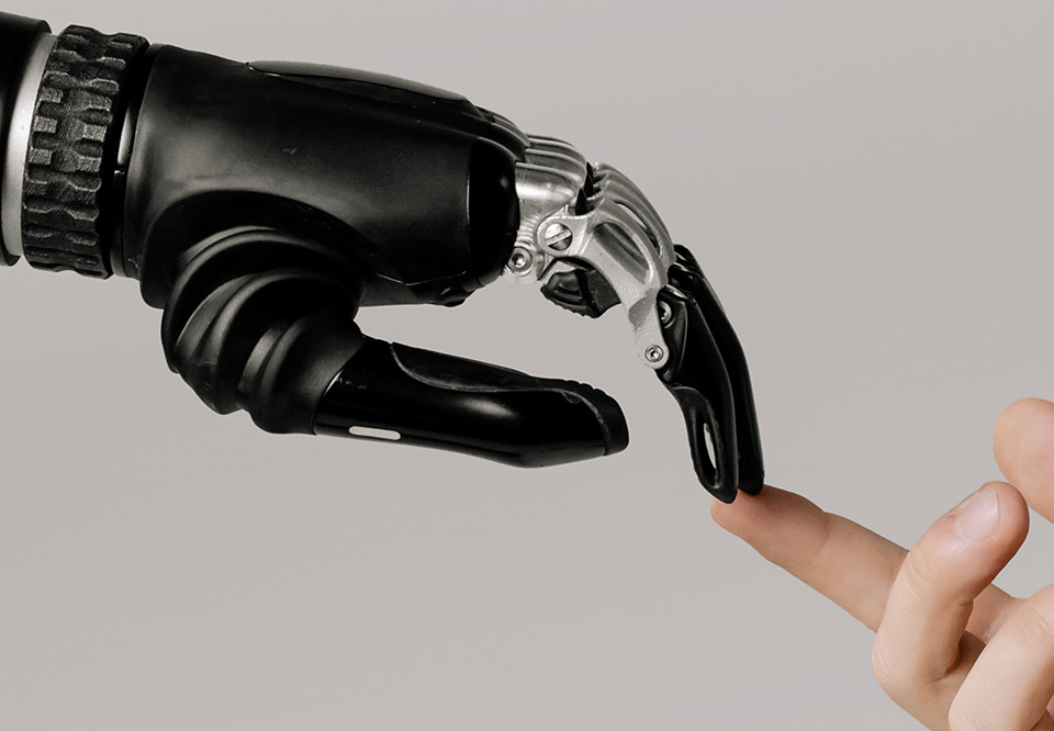 A photo of a robot hand touching a human hand