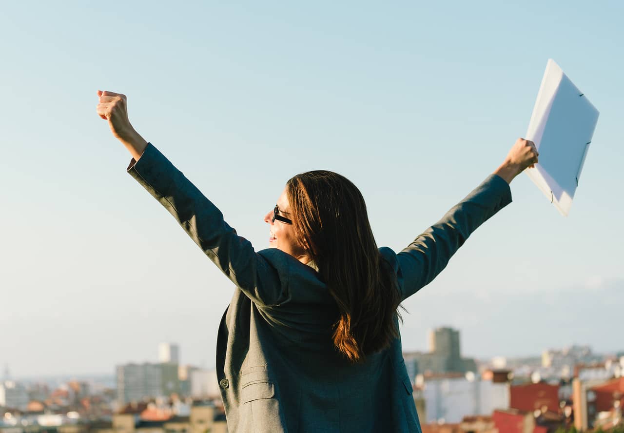A happy business person with their arms up looking over a city scene