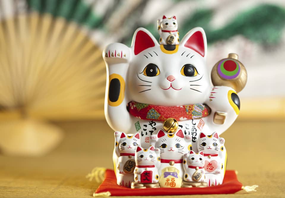 A Maneki Neko cat with many smaller cats.