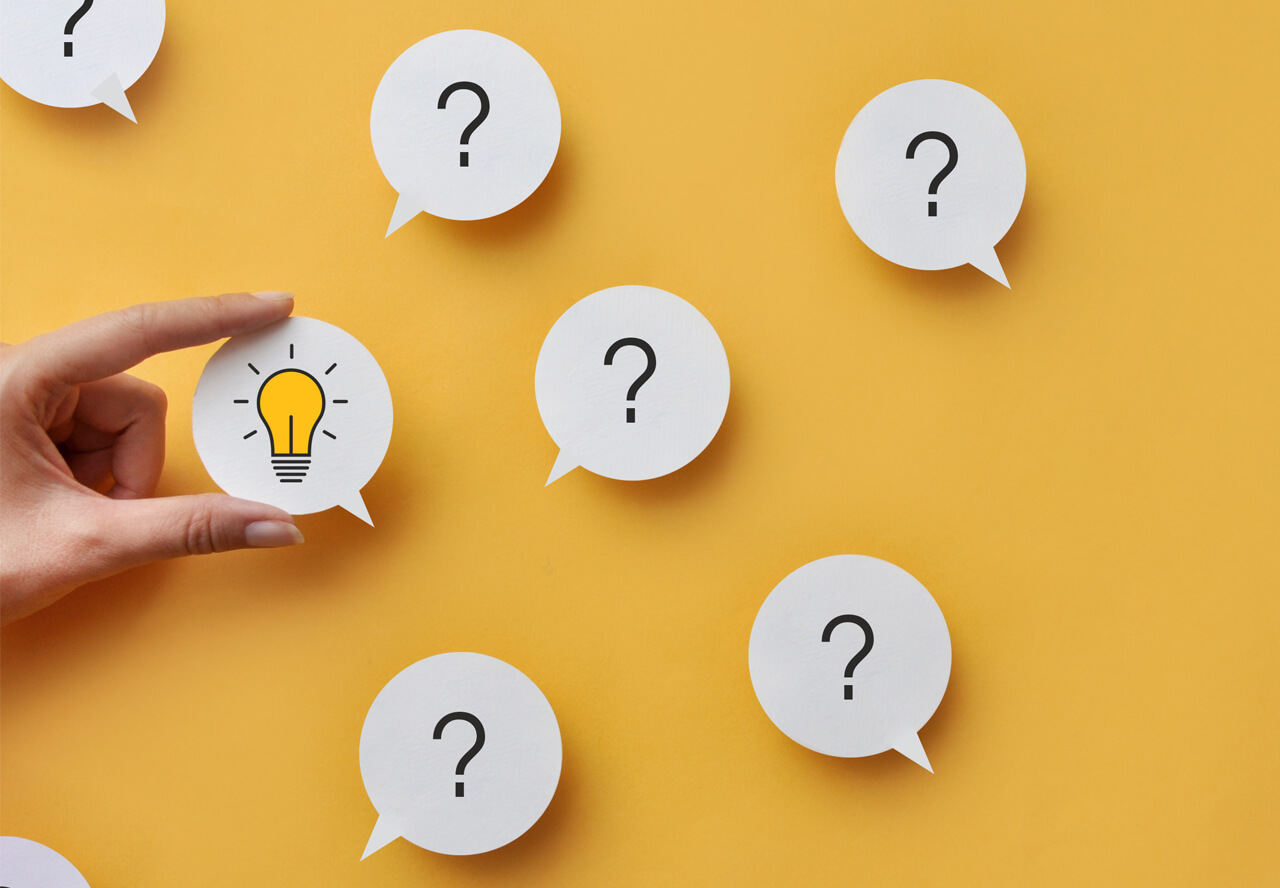 A yellow background with 5 speech bubbles with question marks. A hand can be seen coming from the right holding another bubble with a lightbulb graphic in it
