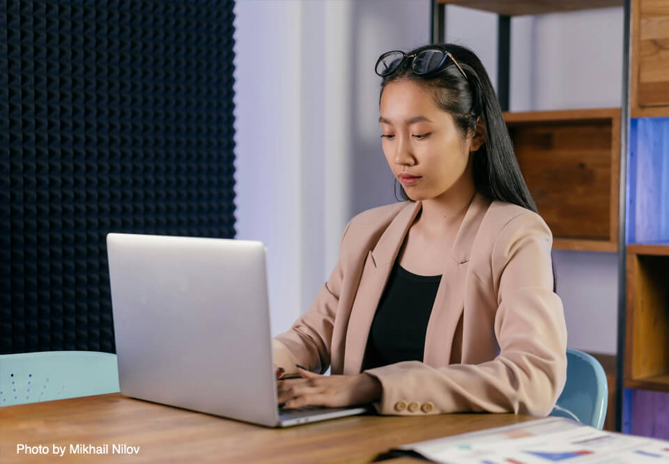A photo of a person sitting at a desk and typing on a laptop computer