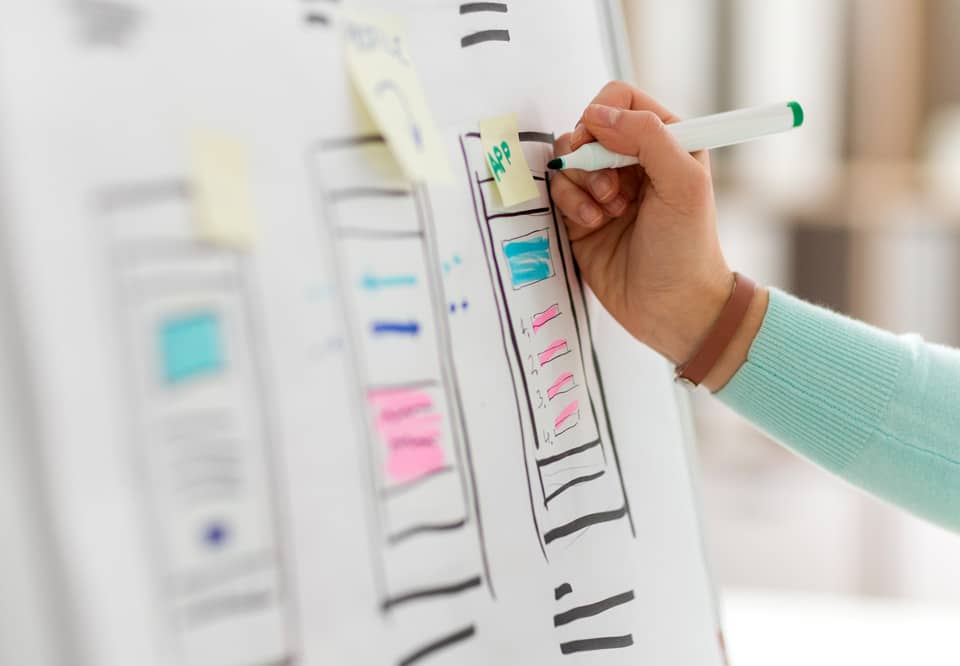 A photo of someone drawing out mobile user interface design for a website